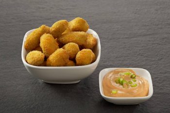 Knusprige Snacks mit Dip auf Schieferplatte Eine Schale mit knusprigen Snacks neben einer Schale mit cremigem Dip serviert auf einer Schieferplatte