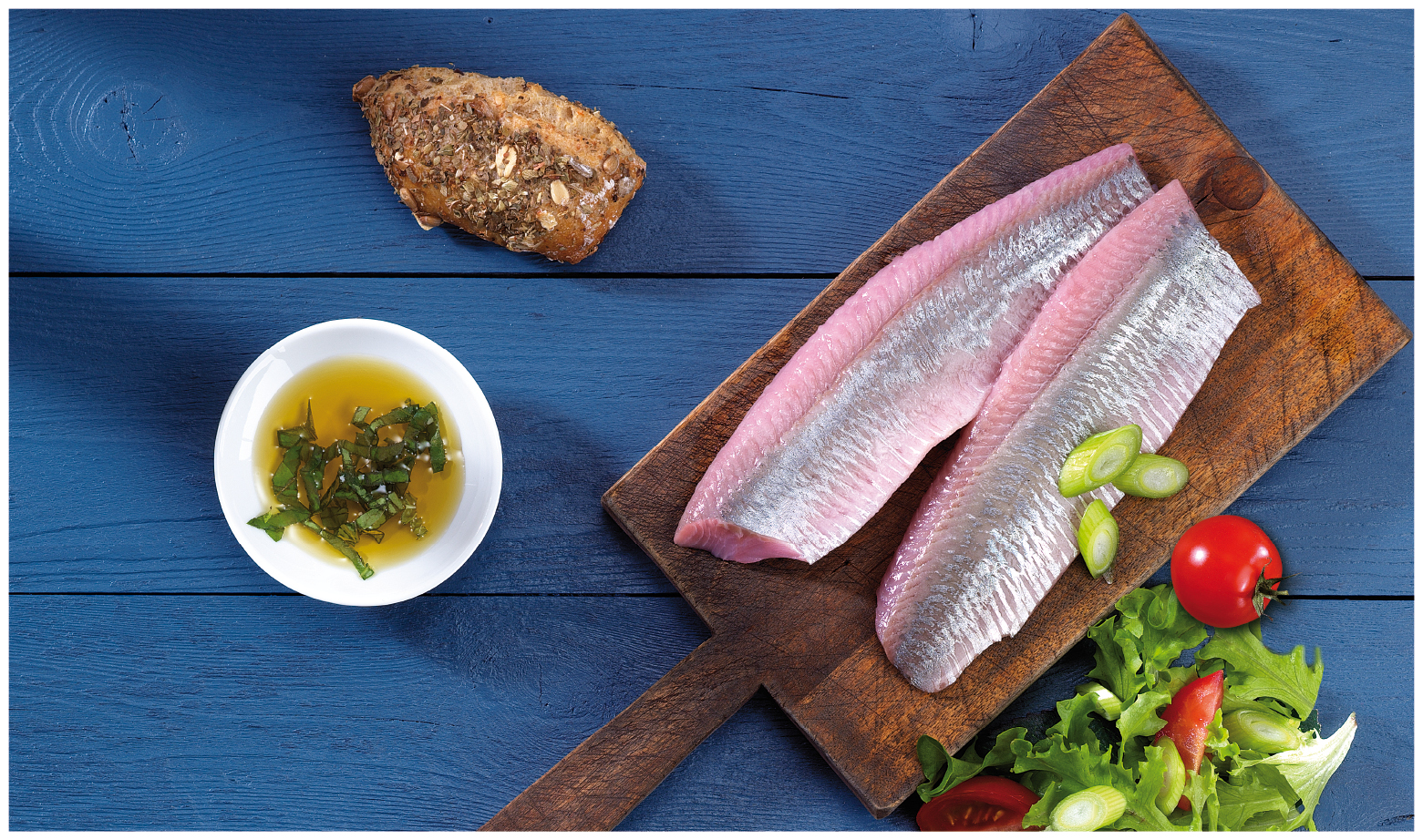 Frische Fischfilets mit Salat und Dip auf Holzbrett Fischfilets auf Schneidebrett mit Salat, Tomaten, Zwiebeln und Dip auf blauem Hintergrund