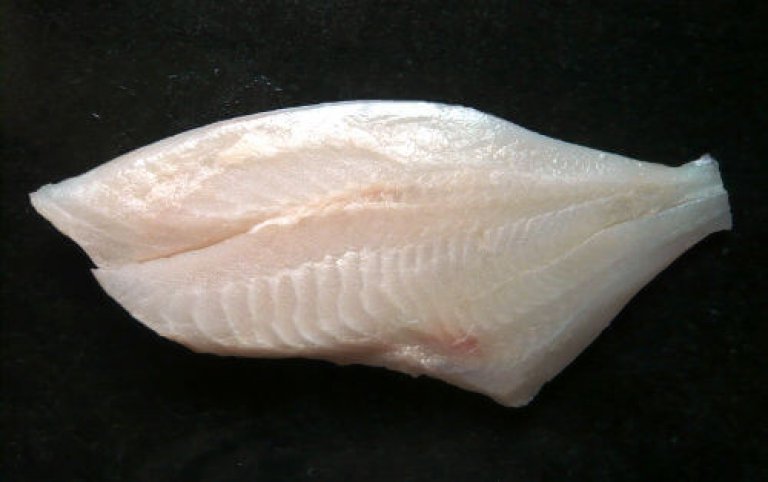 Frisches Fischfilet auf schwarzem Hintergrund Ein rohes Fischfilet liegt auf einem dunklen Untergrund, bereit zum Zubereiten.