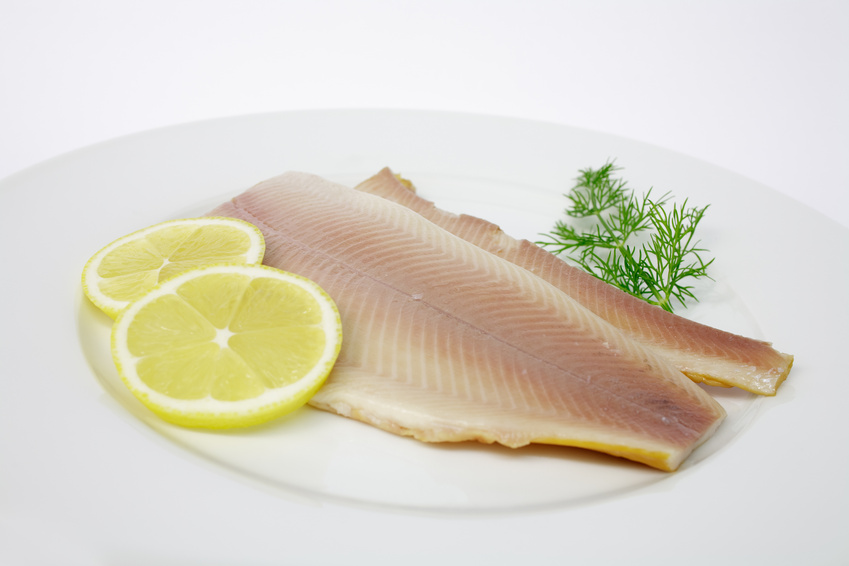 Frisches Fischfilet mit Zitronenscheiben und Dill auf Teller Zwei Fischfilets auf einem Teller, garniert mit Zitronenscheiben und frischem Dill