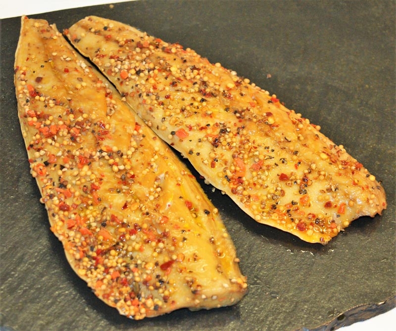 Gewürzter geräucherter Fisch auf Schieferplatte Zwei mit Gewürzen bedeckte Fischfilets auf einer dunklen Schieferplatte